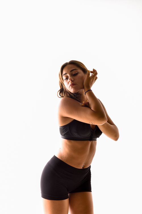 Free Youthful woman posing gracefully in a studio setting, wearing black lingerie and shorts. Stock Photo