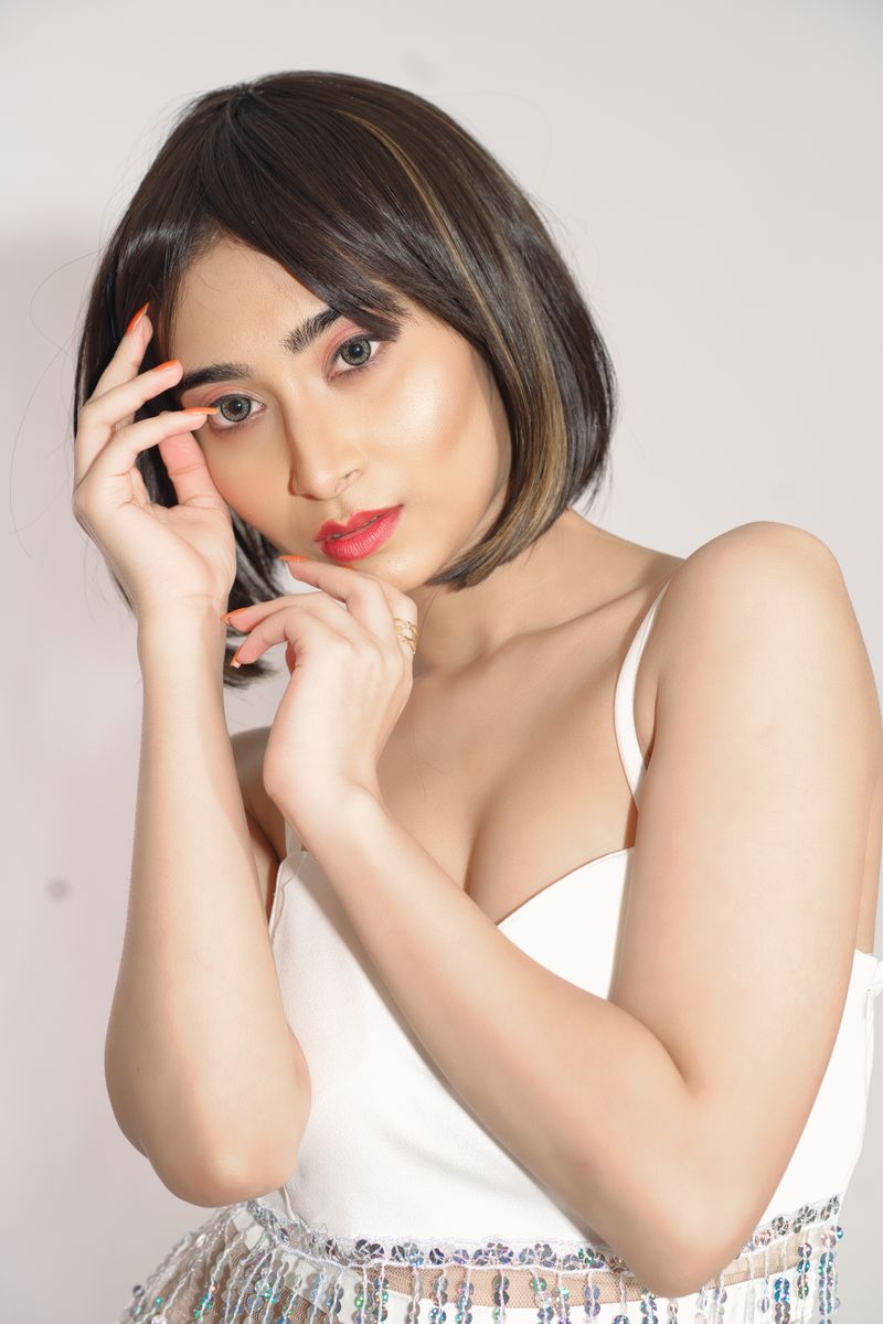 Elegant portrait of a woman with short hair posing in a white top.