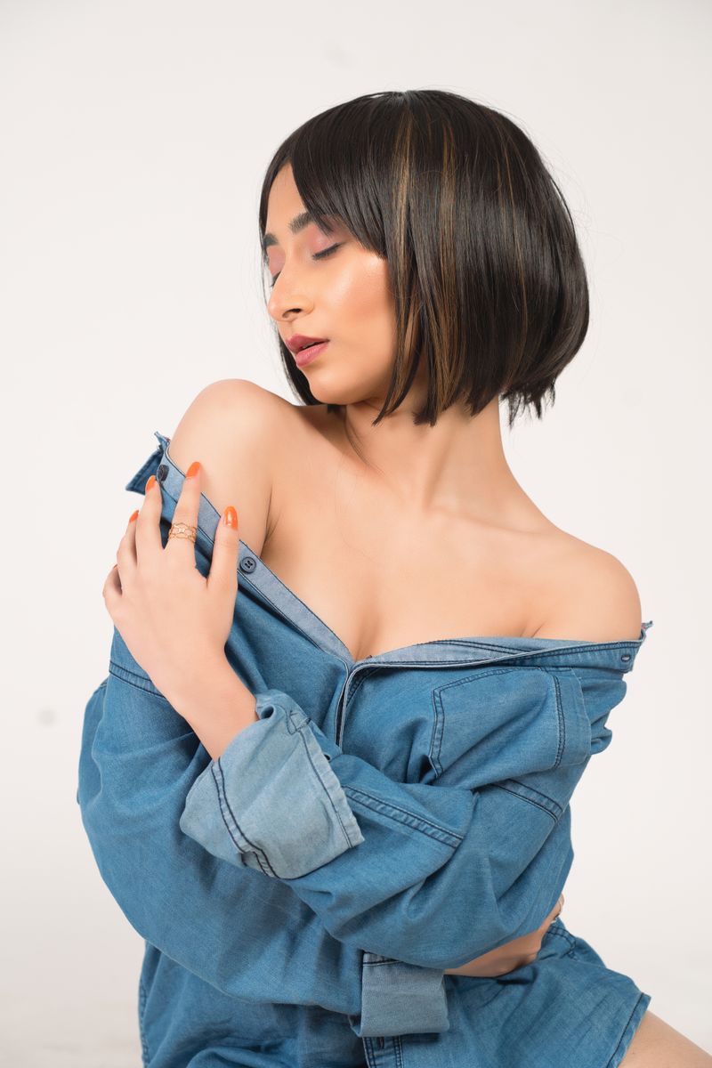 Stylish portrait of a woman with short hair and denim dress, posing with elegance and minimalism.