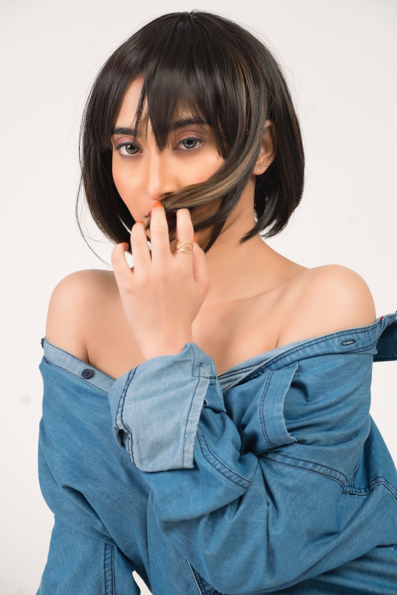 Beautiful portrait of a woman with short hair partially covering face, posing in a denim jacket.