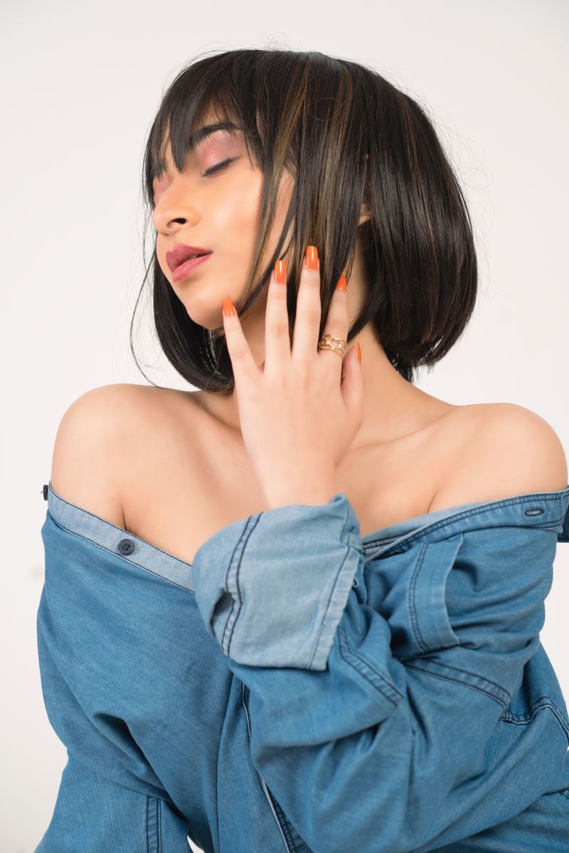 Elegant portrait of an Asian woman in a denim jacket with short hair and eyes closed, posing gracefully.