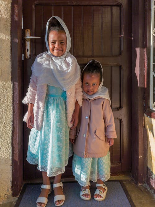 Young Girls in Blue Dress Standing In Front of the Door