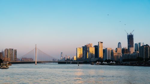 Free Scenic view of a modern city skyline with a bridge at dusk, reflecting in the river. Stock Photo