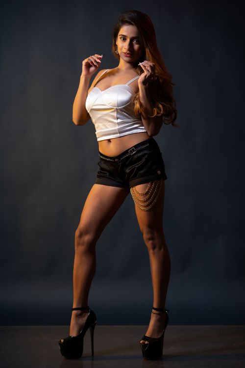 Free Stylish studio portrait of a woman in high heels, posing elegantly against a dark backdrop. Stock Photo
