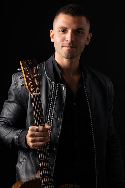 Portrait of a Young Man Wearing a Leather Jacket Holding a Bass Guitar