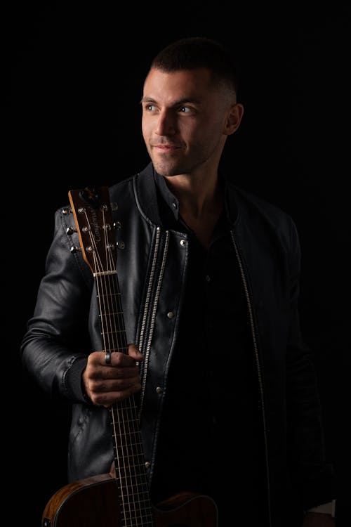 Man in Black Leather Jacket Holding Guitar