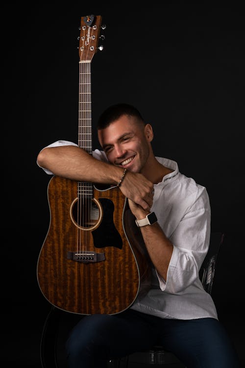 Man with White Long Sleeves Holding a Wooden Guitar
