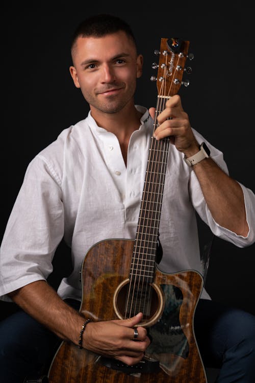 A Man in White Button Up Shirt Holding a Brown Acoustic Guitar