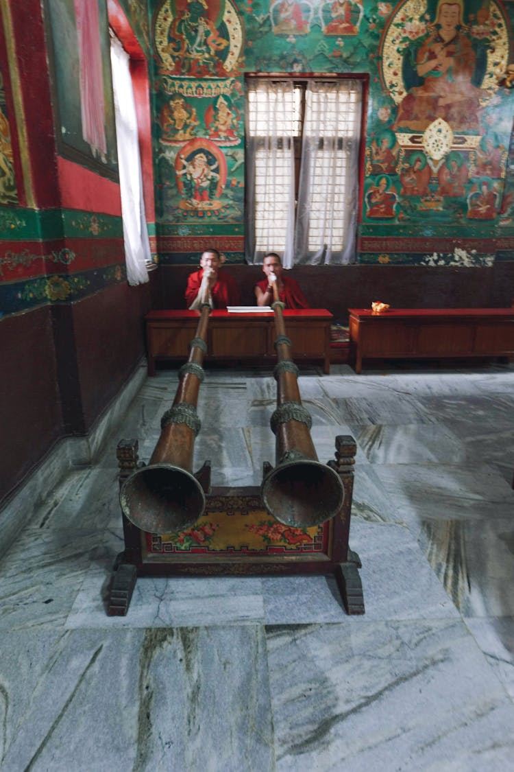 Two Monks Blowing In Tibetan Horns Placed Indoors