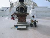 Men cleaning a historic Buddhist temple in Nepal, preserving cultural heritage.