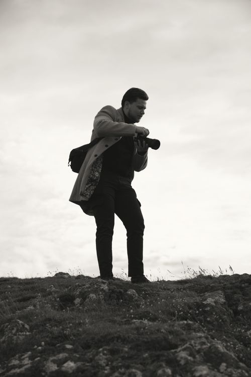 Free A silhouette of a man with a camera standing on a hilltop, capturing a serene outdoor scene. Stock Photo