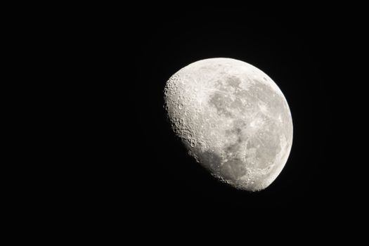 Detailed view of the Moon phase with visible craters against a dark night sky.