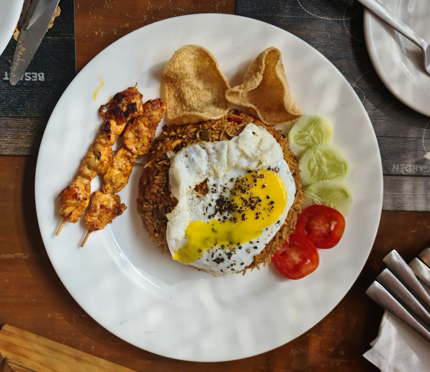 Riz Jollof nigérian fumant servi avec des bananes aloko et du poulet grillé