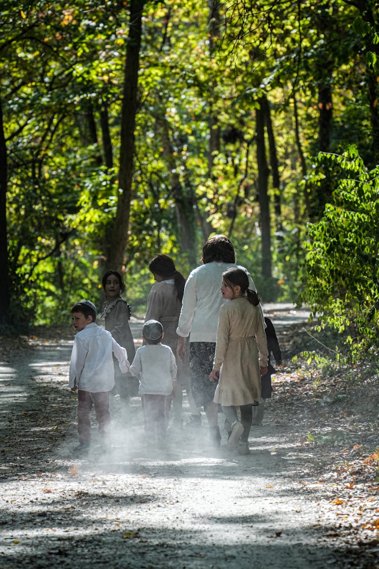 Woman With A Group Of Children Walking In A Forest 