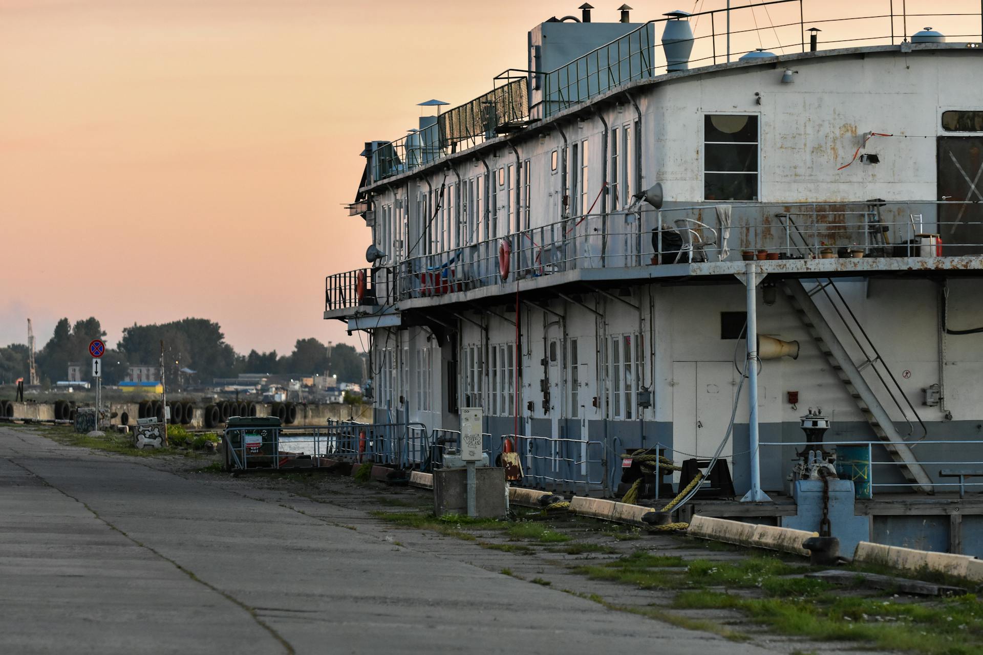 A deserted shipyard with an old boat docked along the quay at sunset in Riga, Latvia.