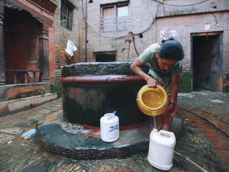 A Woman Pouring Water Into A Bottle 