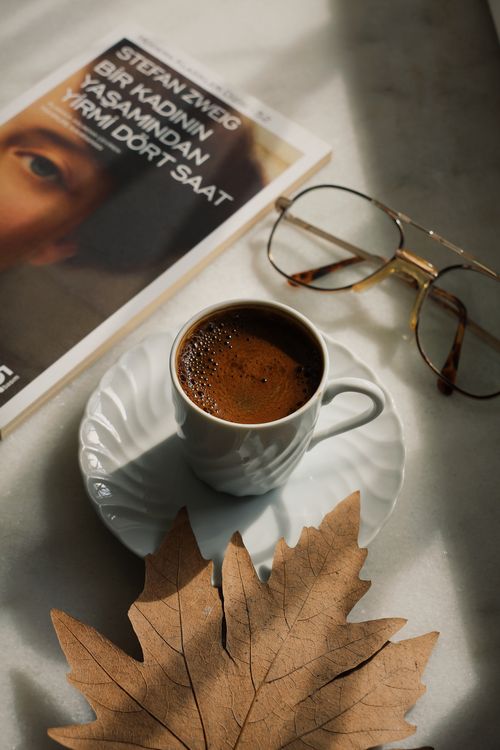 Free Stylish coffee cup with a book and glasses on a marble surface, artistic arrangement. Stock Photo