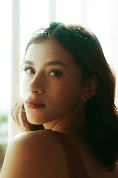 Close-up portrait of a young woman with brunette hair and soft natural lighting indoors.