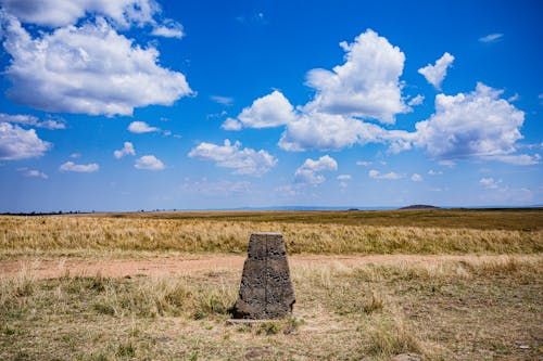 Rock in the Middle of Brown Grass Field Under Blue Sky