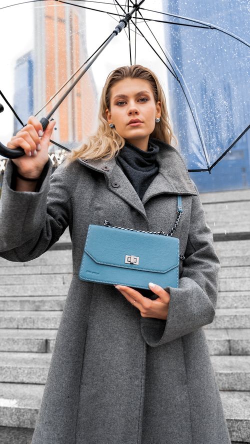 Free Elegant woman showcasing a blue handbag under a transparent umbrella on a rainy day. Stock Photo