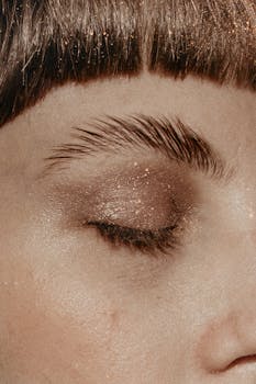A detailed close-up of a woman's eye with glittery eyeshadow in a monochrome palette.