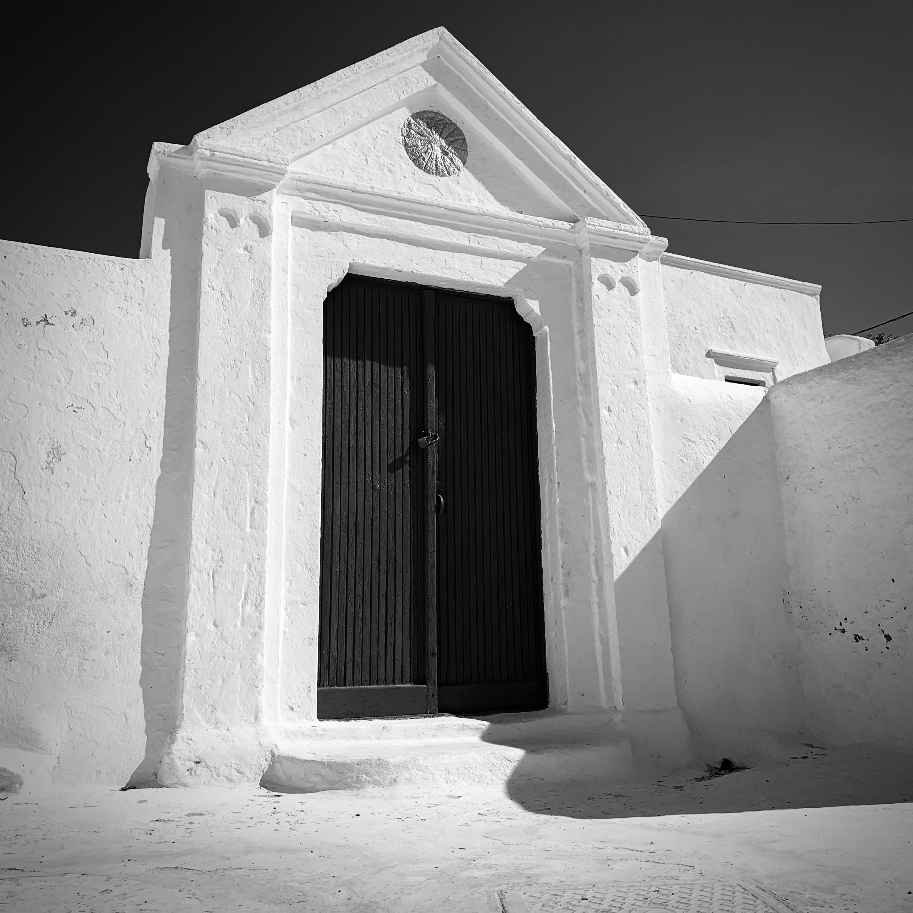 Black and white photo of a vintage doorway in Pyrgos, Greece with classic architectural style.