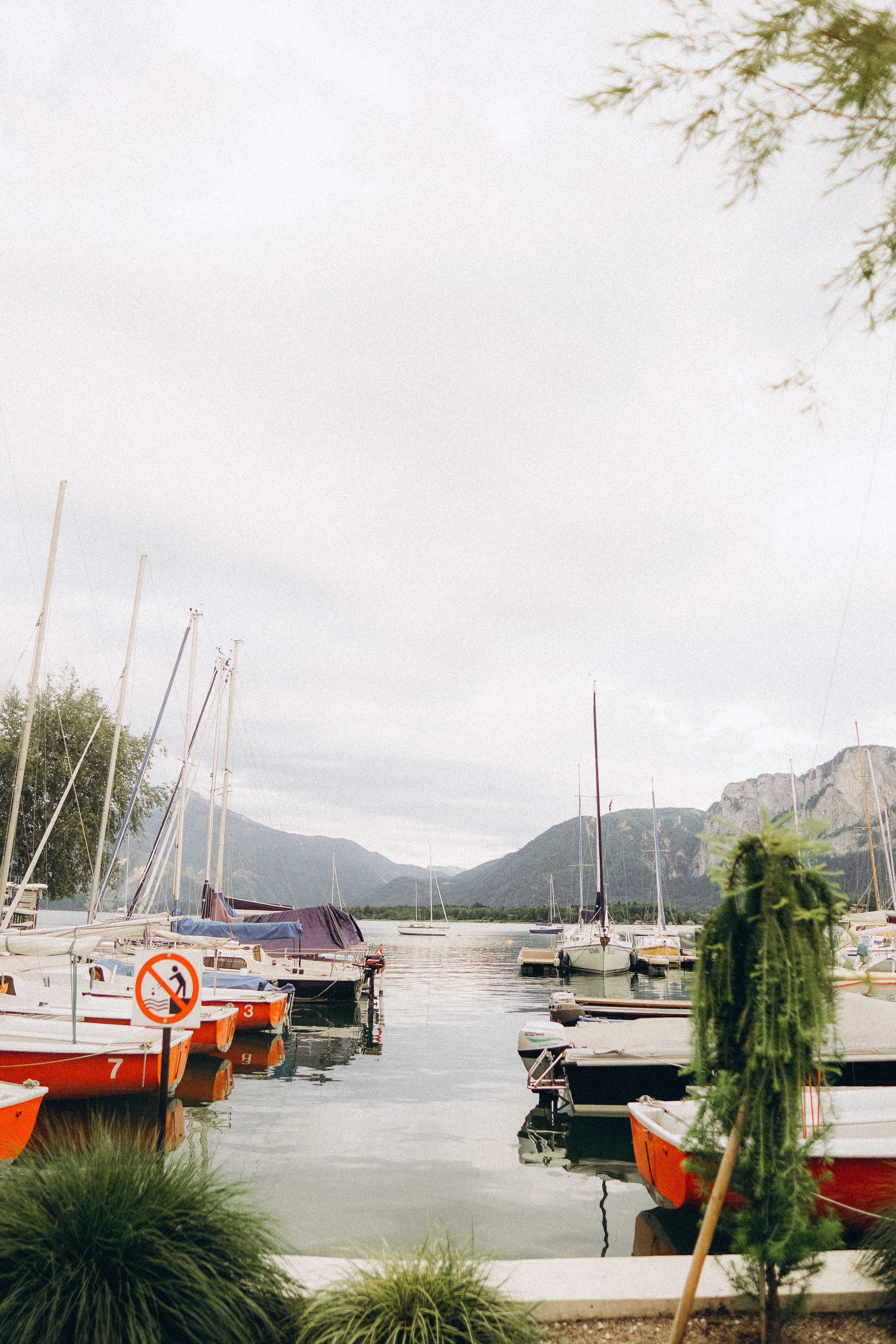 Beautiful view of sailboats docked in a harbor with mountains in the background.