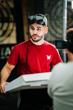 A man in a red shirt using a virtual reality headset indoors during a photoshoot.