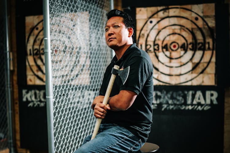 A Man In Black Shirt Holding An Axe