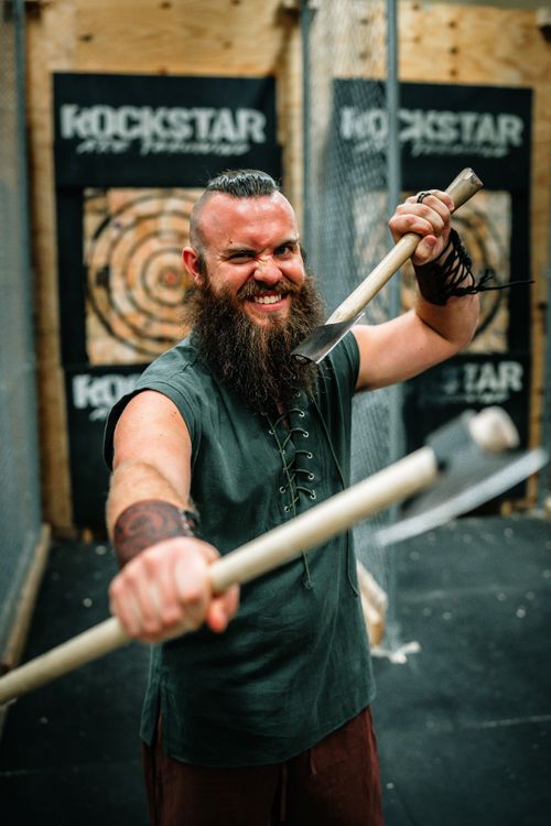 Free Energetic man in Viking style costume holding axes in an indoor setting. Stock Photo