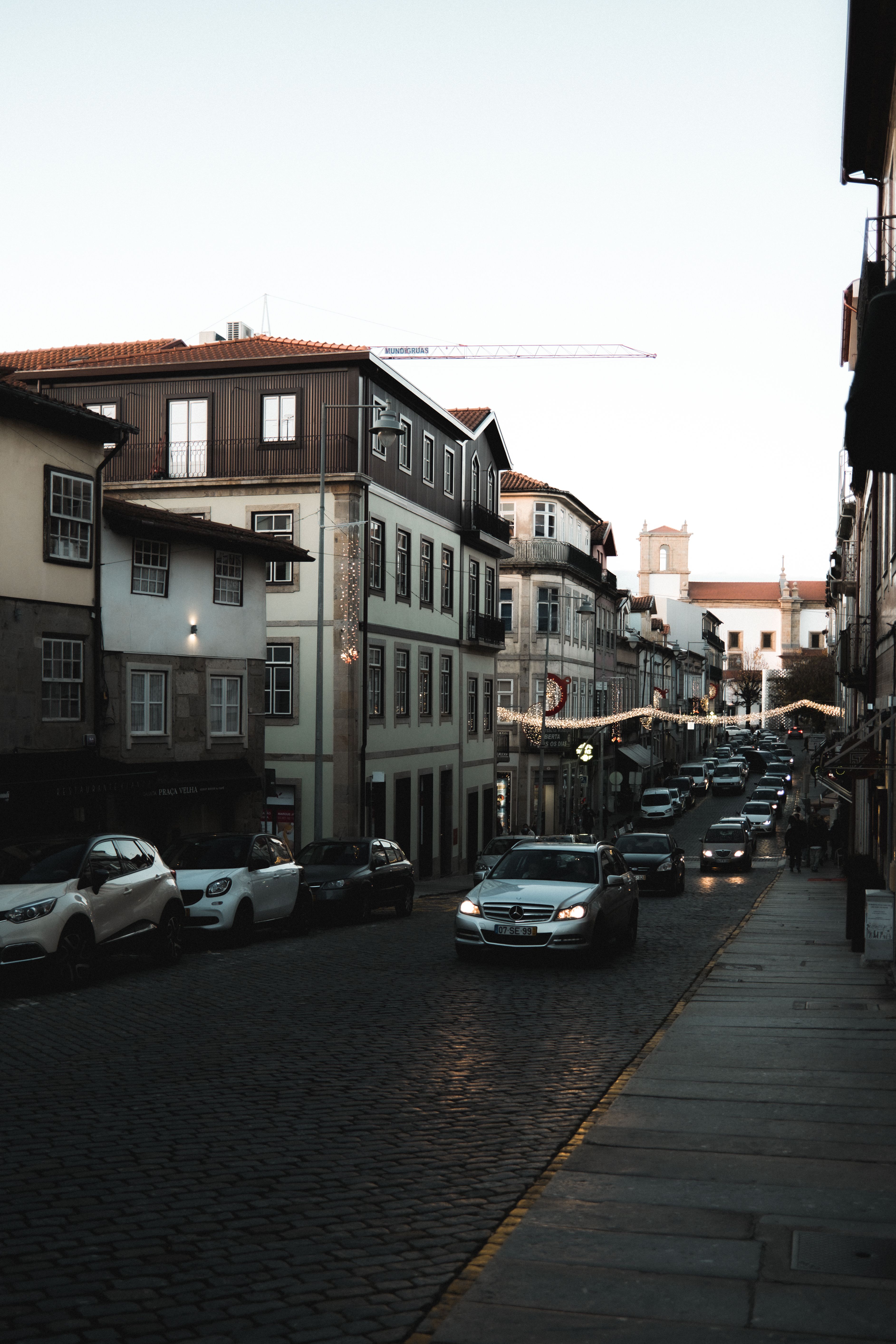 Cars Parked and Driving on a Cobblestone Street · Free Stock Photo