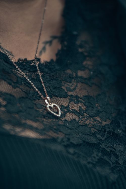 Free Close-up of a silver heart pendant necklace elegantly displayed on black lace fabric. Stock Photo