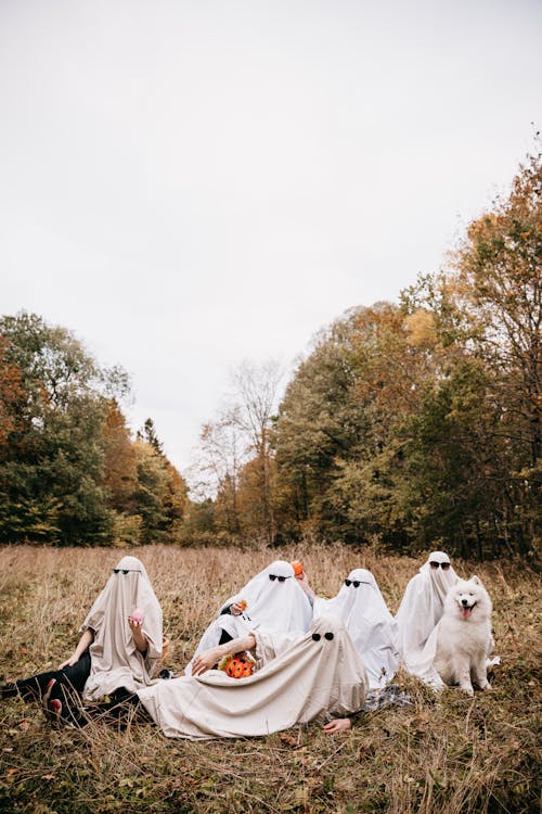 People in Ghost Costumes Sitting on Grass