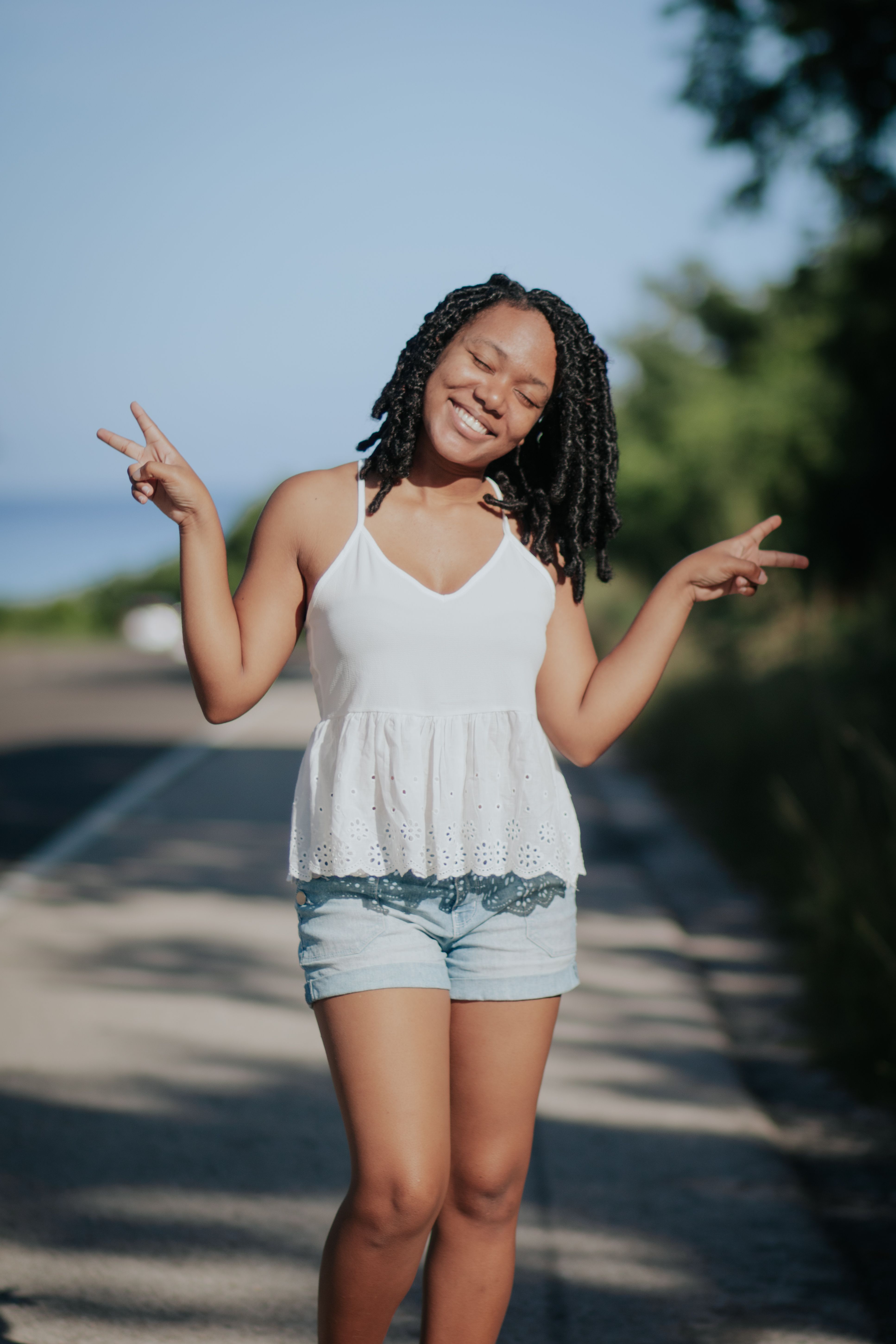 Woman in White Tank Top and Denim Shorts Standing on the Street while ...