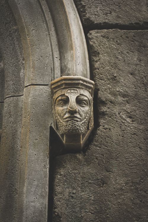 Free Detailed stone sculpture of a knight's head mounted on a historic wall. Stock Photo