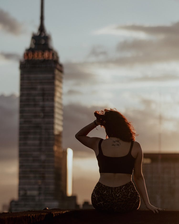 Woman Sitting On Building Edge With View On City