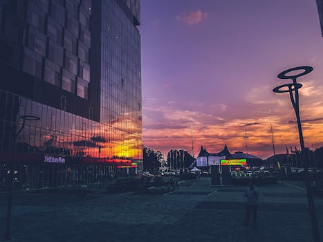 Colorful sunset reflecting on modern buildings in Bucharest urban scene.