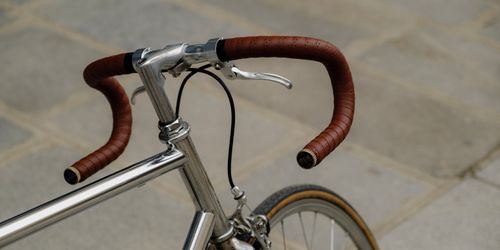 Free Close-up of a vintage bicycle's brown leather handlebar tape on a stone pavement. Stock Photo