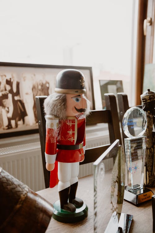 Decorative nutcracker soldier among various awards on a desk with framed photos in the background