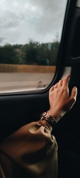 A hand elegantly resting on a car window, capturing the essence of travel and calmness.