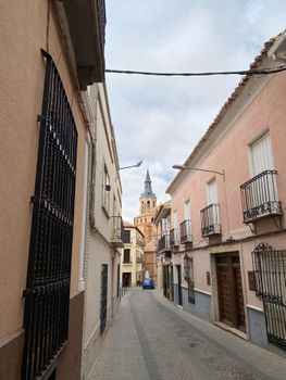Picturesque narrow street view featuring historic buildings and a church spire.