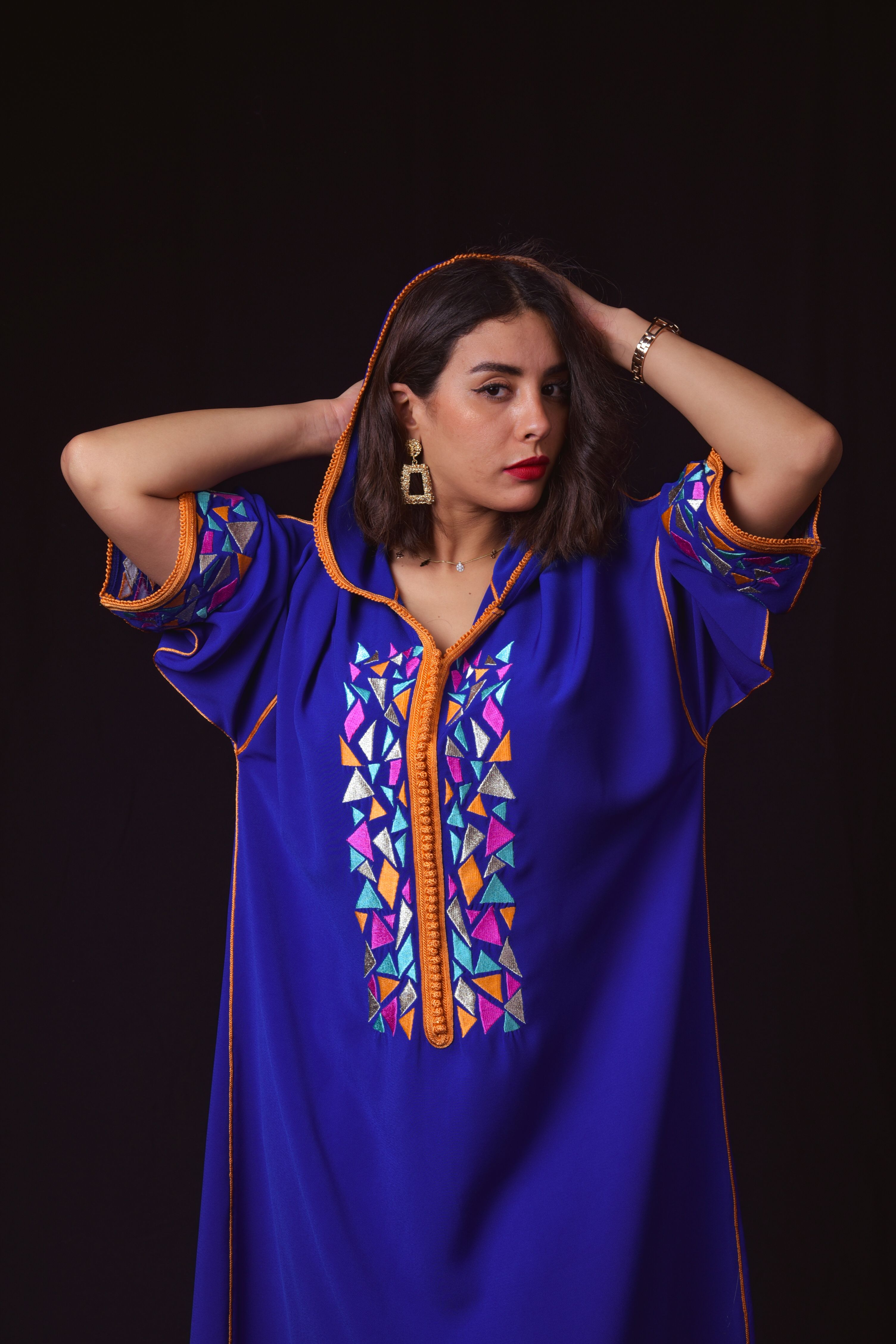 Portrait of a woman in a colorful traditional dress against a black background.