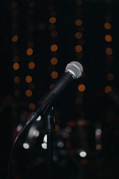 Close-up of a microphone with a blurred bokeh light background, capturing a musical ambiance.