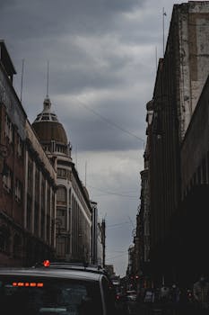 Dramatic urban view of Mexico City buildings under an overcast sky at dusk.