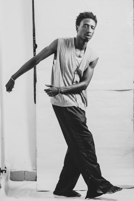 Artistic monochrome portrait of a black man in stylish clothing; vertical shot with dynamic pose.