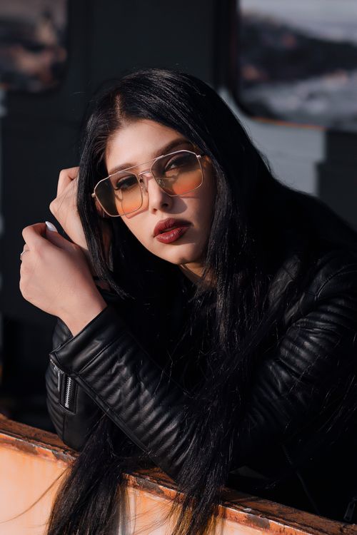 Free Fashionable woman posing confidently in a black leather jacket and sunglasses. Stock Photo