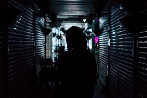 Free A silhouette of a person in a backlit dark urban alley, creating a mysterious atmosphere. Stock Photo