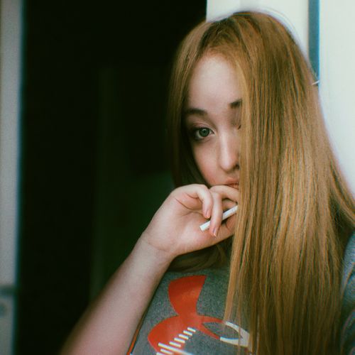 Free Portrait of a young woman with long brown hair posing thoughtfully indoors. Stock Photo
