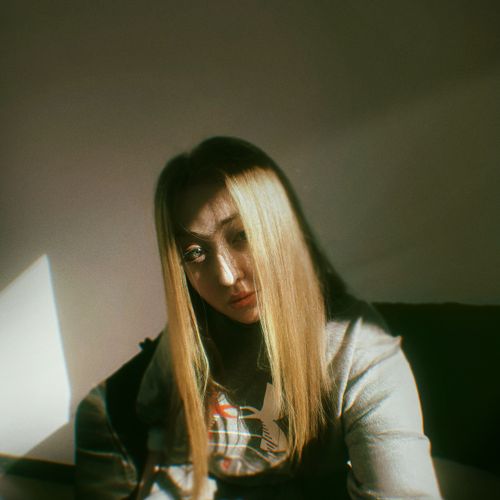 Free Artistic portrait of a woman with long hair in natural light, creating a moody effect. Stock Photo