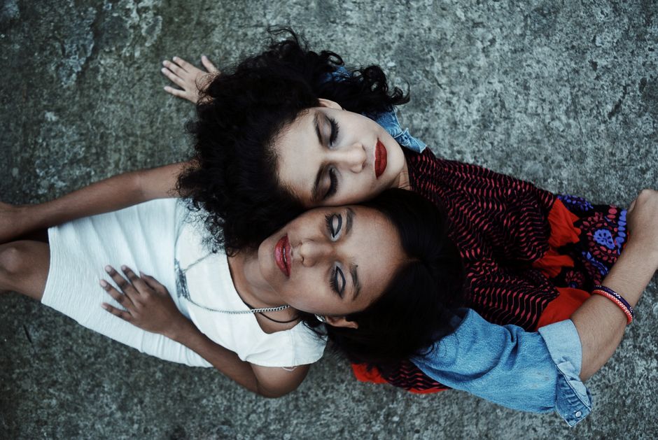 Aerial view of two women lying on concrete, embracing and relaxing together in Patna, India.
